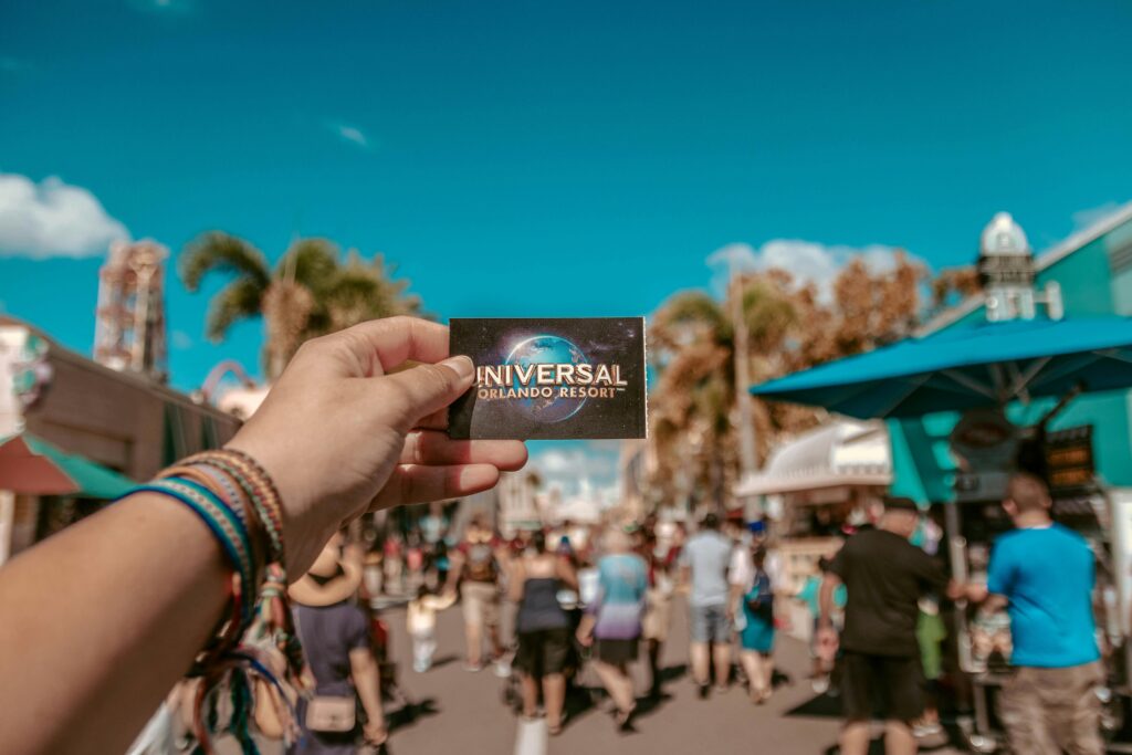 pexels-photo-1860618-1860618 A hand holding a Universal Orlando Resort ticket in a bustling theme park setting.